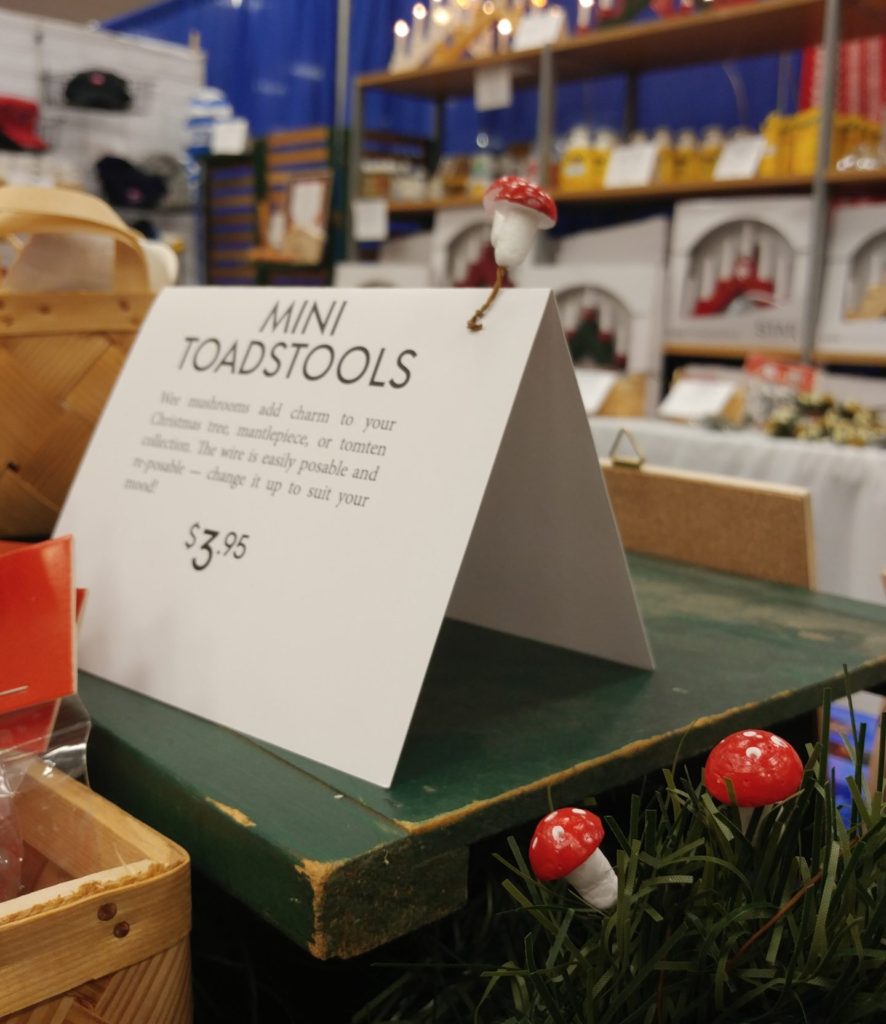 Product information sign next to miniature decorative toadstools.